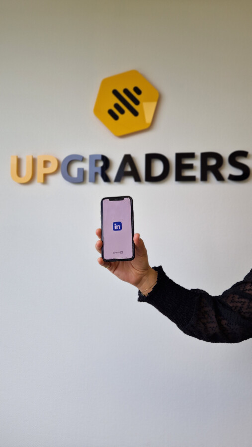 Het upgraders logo met daaronder een telefoon waarop het logo van LinkedIn te zien is.